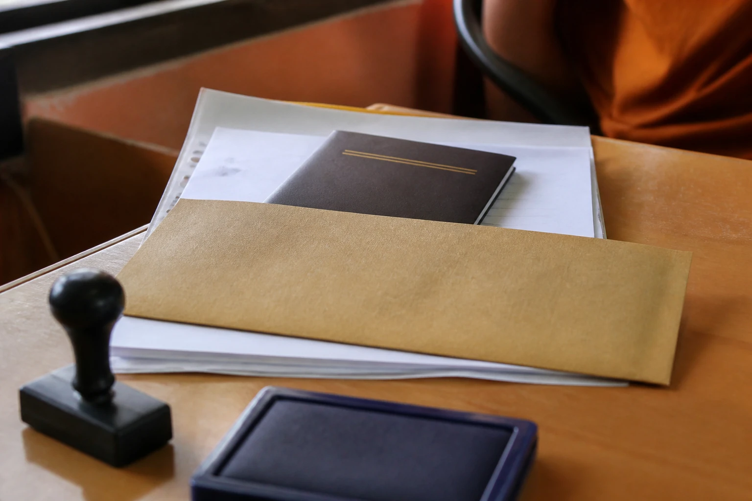 เล่มหนังสือเดินทางแรงงานต่างด้าววางบนโต๊ะพร้อมซองเอกสาร เตรียมยื่นตรวจลงตราวีซ่าที่ตรวจคนเข้าเมือง